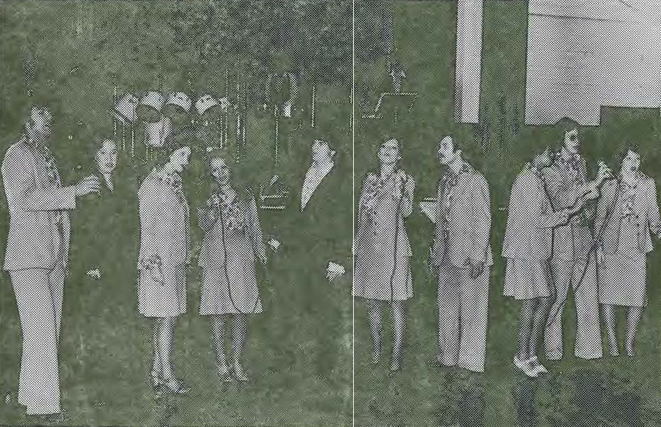 A group of people, dressed in coats and suits, stand and talk in pairs indoors. The background includes geometric shapes and a row of chairs. The image has a grainy, black-and-white appearance.